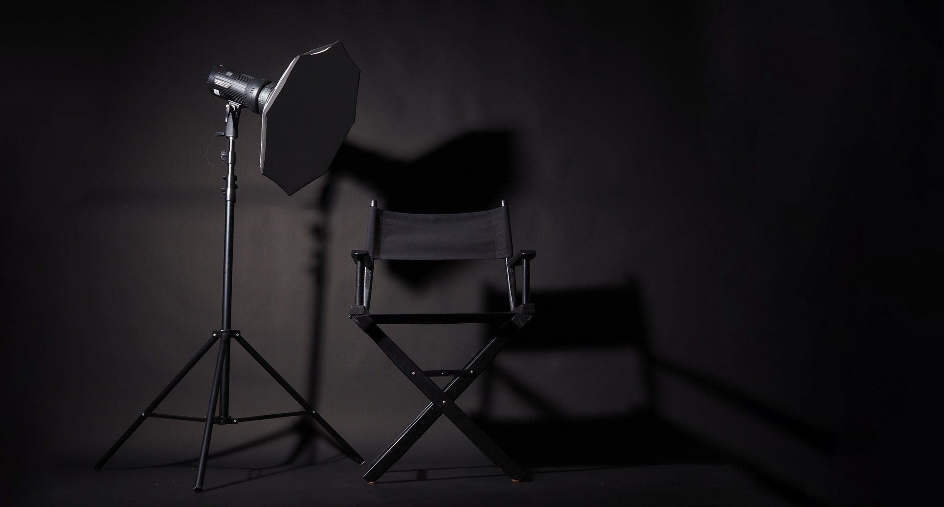 Black Director chair and studio light on black background.